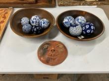 Pair of wooden bowls with blue and white pattern glass balls and pottery sun face