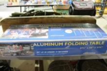 One aluminum folding table and one Roll-a-Table. In boxes.
